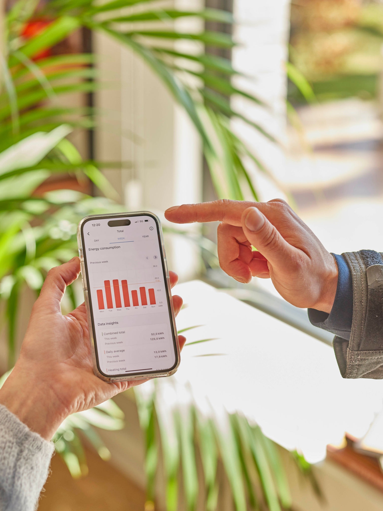 Zwei Leute besprechen zusammen die von einer Smartphone-App angegebenen Daten zum Betriebsverhalten