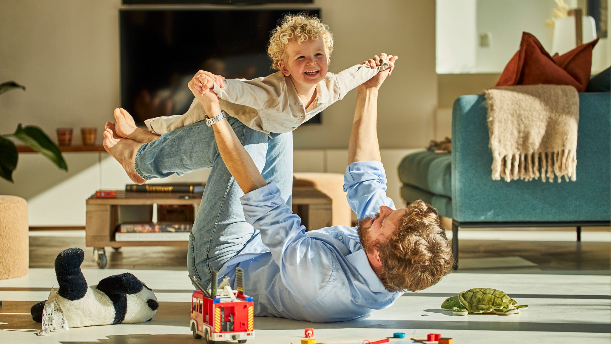 Vater und Kind spielen vergnügt miteinander und genießen die Wärme der Fußbodenheizung
