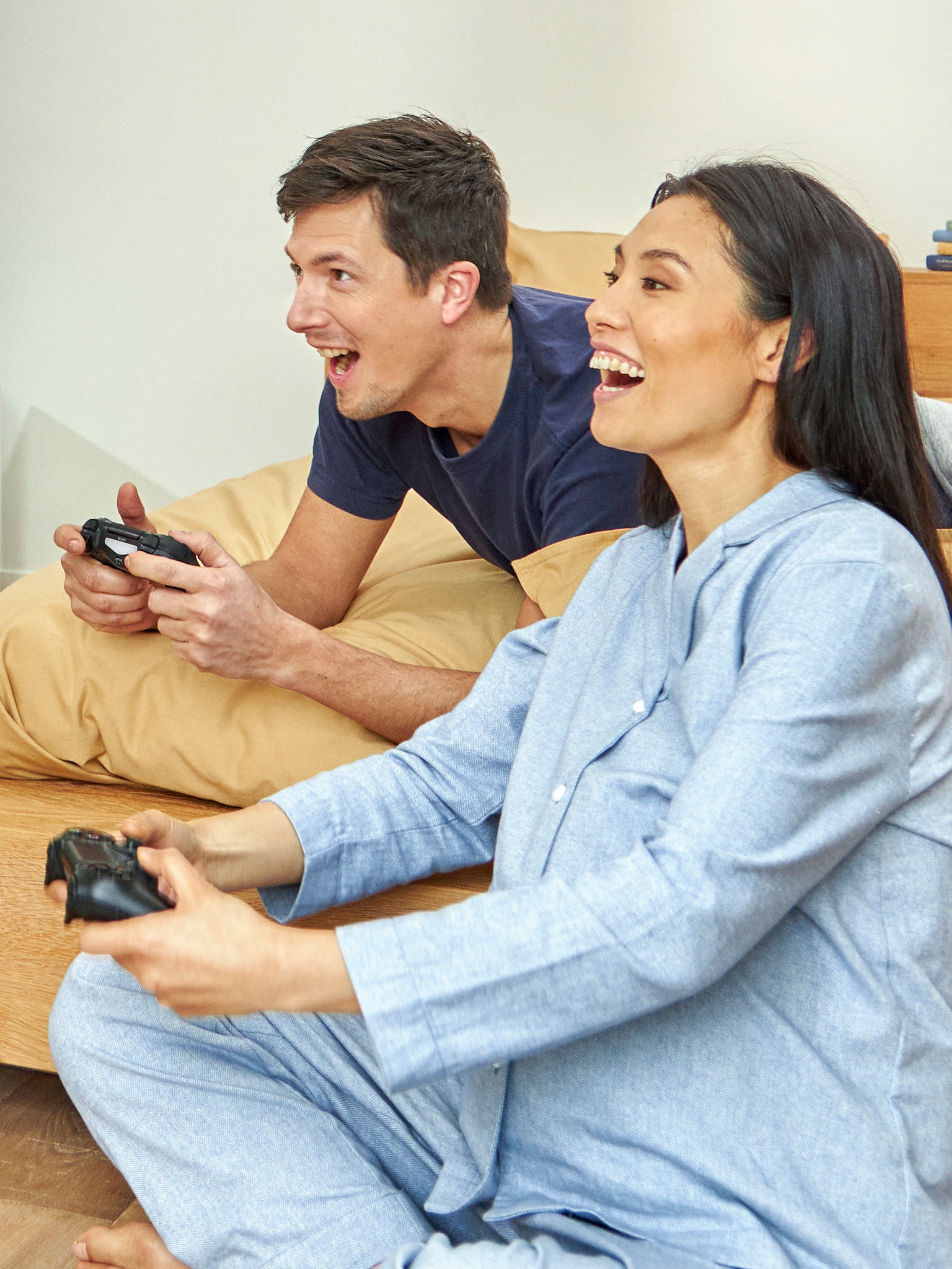 Ein schwangeres Paar spielt im Schlafzimmer ein Videospiel.