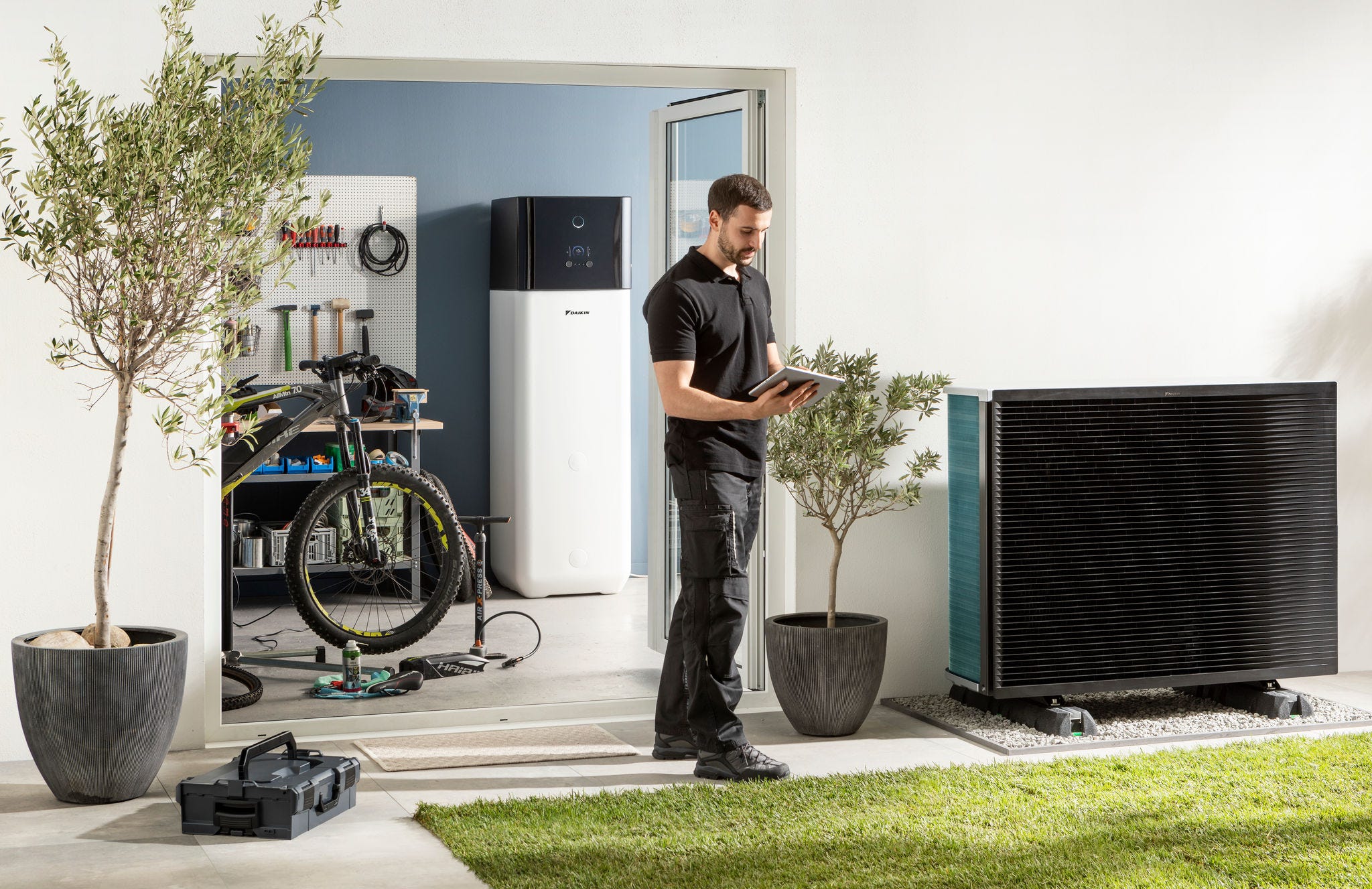 Eine Installationsfirma überprüft ein Außengerät und einen Warmwasserspeicher einer luftgespeisten Wärmepumpe