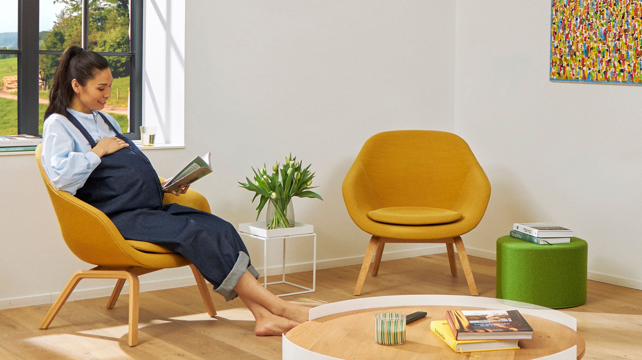 Eine Schwangere liest in einem Sessel und genießt dabei die reine Luft in ihrem Wohnzimmer.