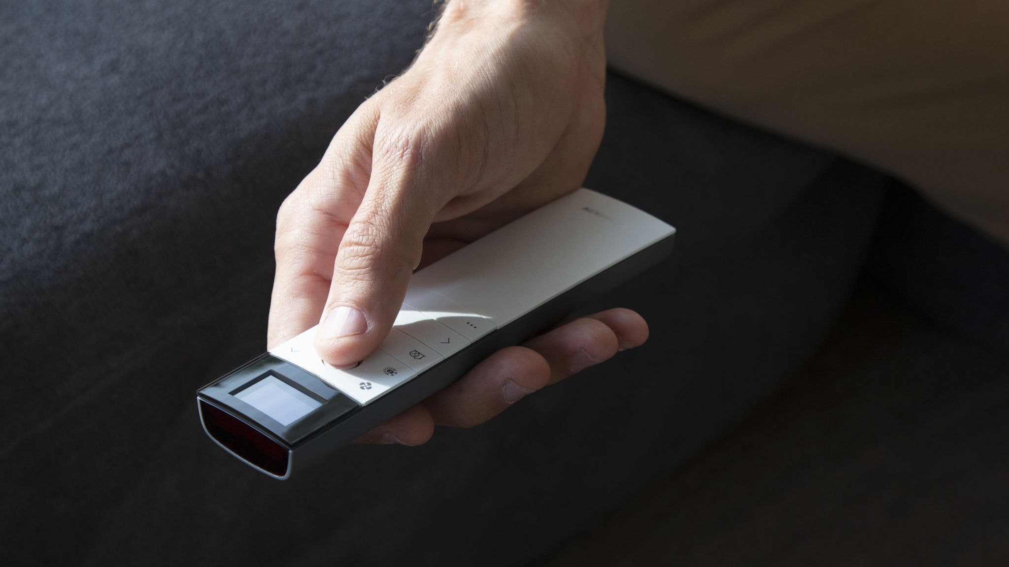 Mann bedient mittels Fernbedienung seine Klimaanlage im Wohnzimmer