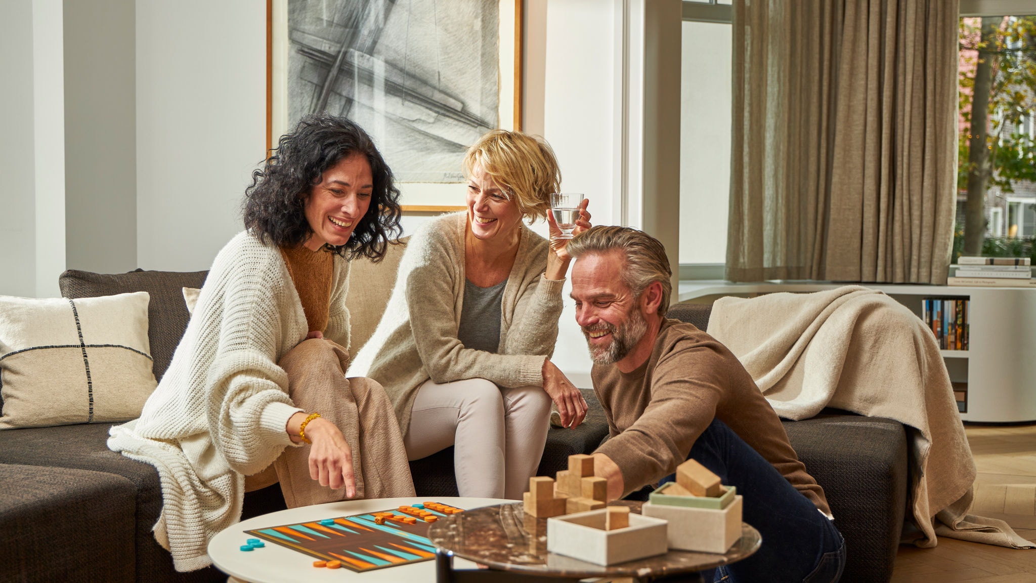 Zwei Frauen und ein Mann spielen ein Brettspiel