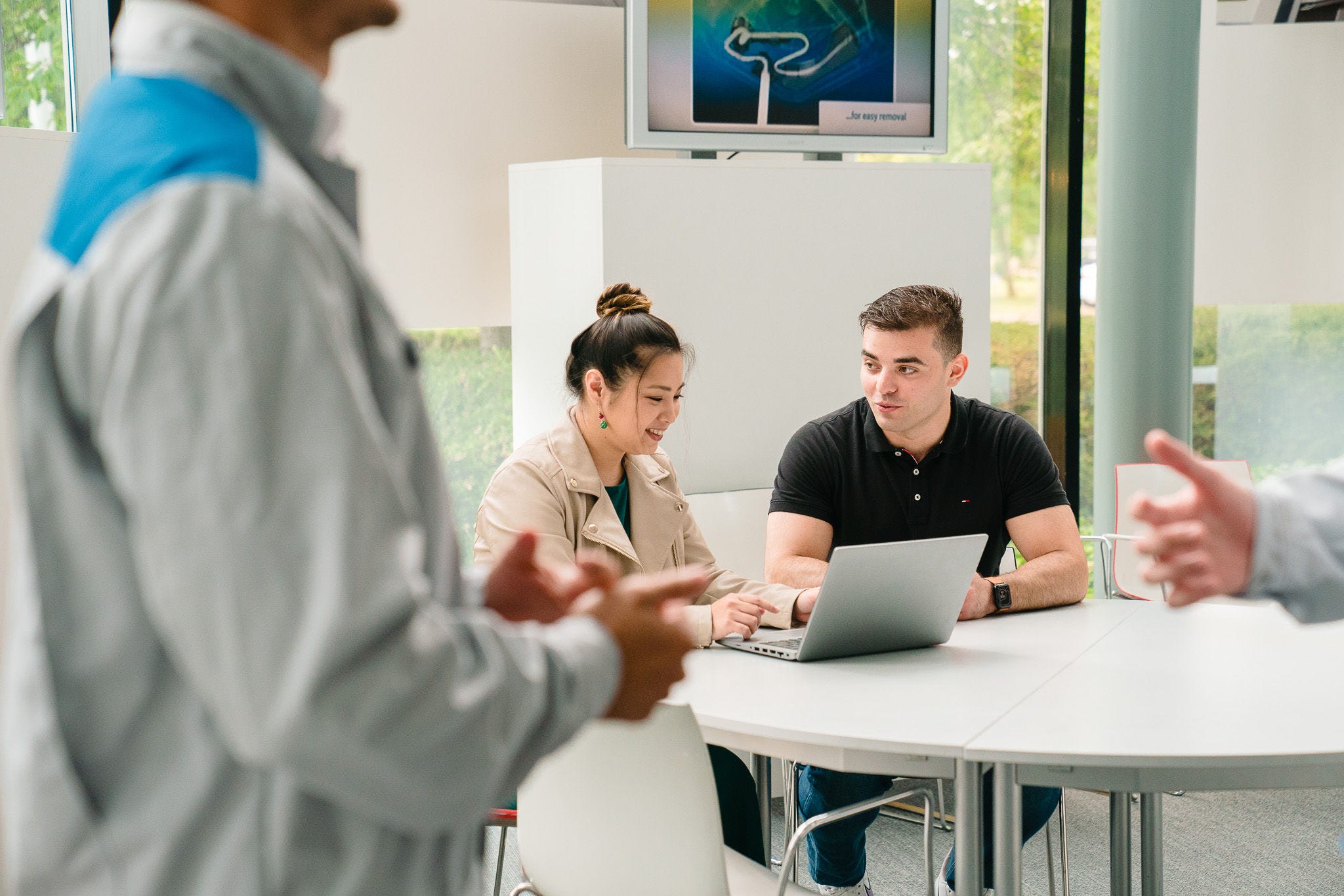 Eine Frau erklärt einem Mann etwas am Laptop