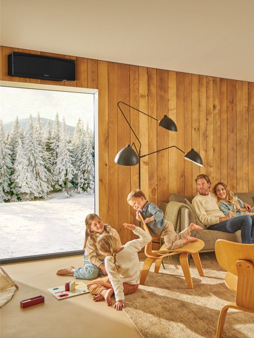 Eine Familie genießt die saubere Raumluft mit dem Daikin Luftreiniger, während die Kinder Schach spielen und die Erwachsenen sich mit Getränken in einem hellen, gut belüfteten Wohnzimmer entspannen