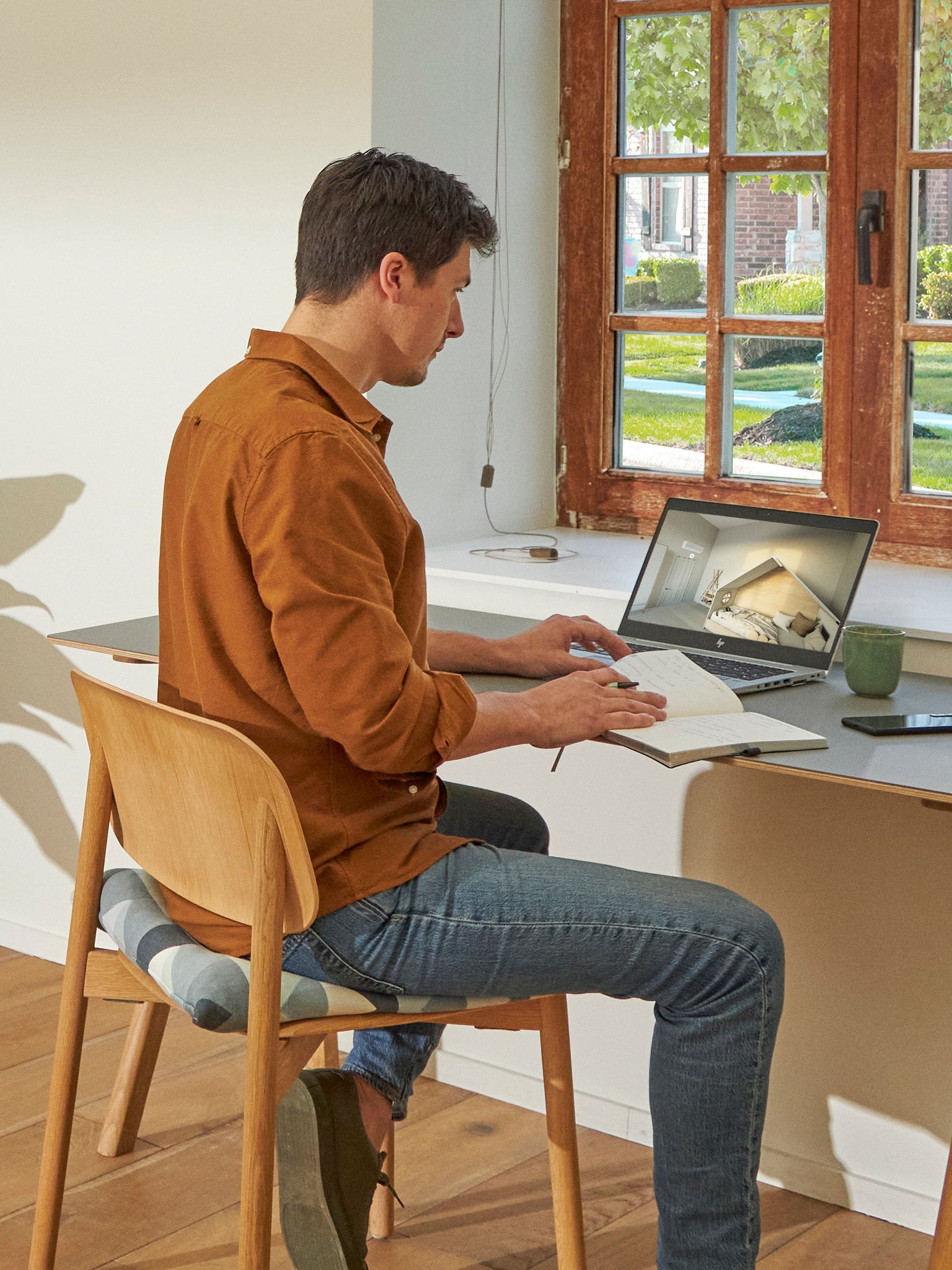 Ein Mann sitzt an seinem Schreibtisch und betrachtet auf seinem Laptop Klimaanlagen im virtuellen Schauraum