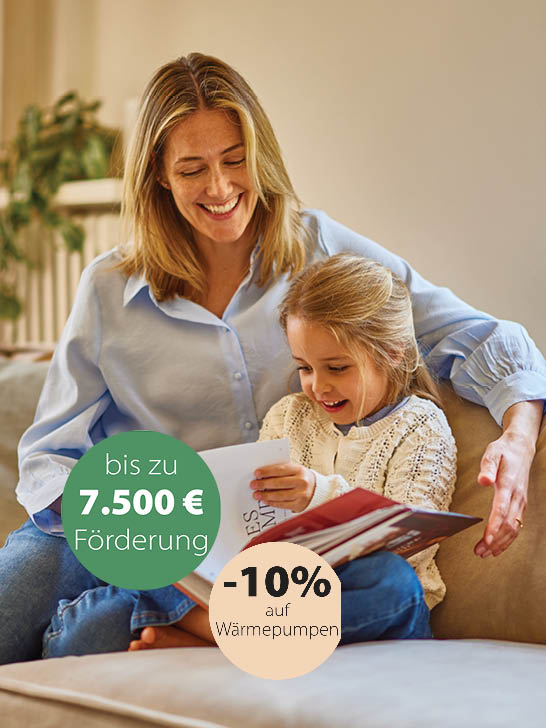 Mutter mit Tochter sitzt am Sofa und sieht ein Buch an