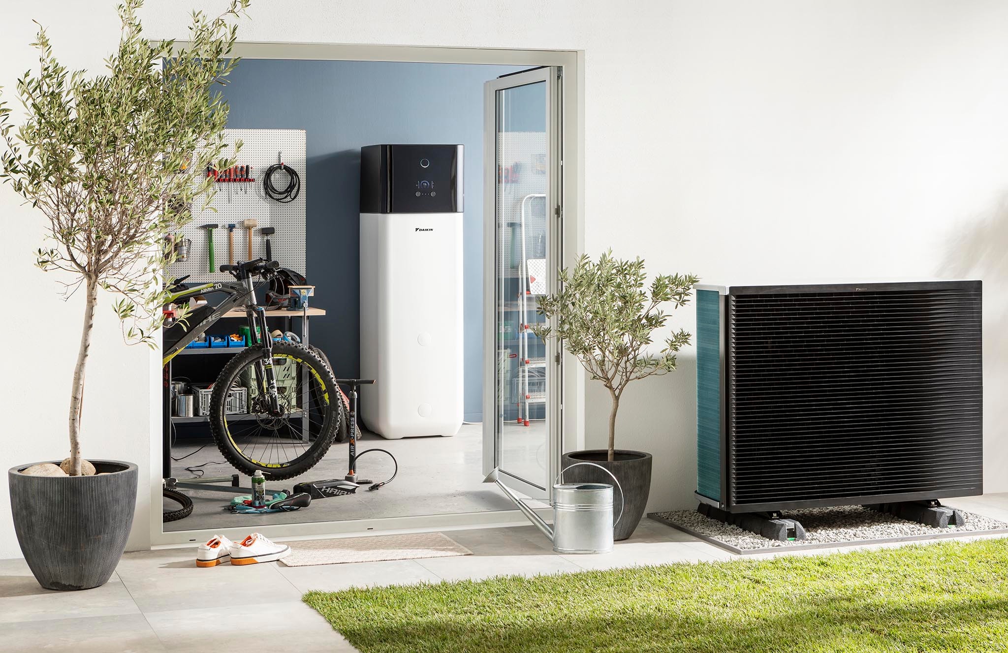 Innengerät einer Luft-Wasser-Wärmepumpe mit integriertem Warmwasserspeicher, aufgestellt im Haus, sowie das im Garten aufgestellte Außengerät