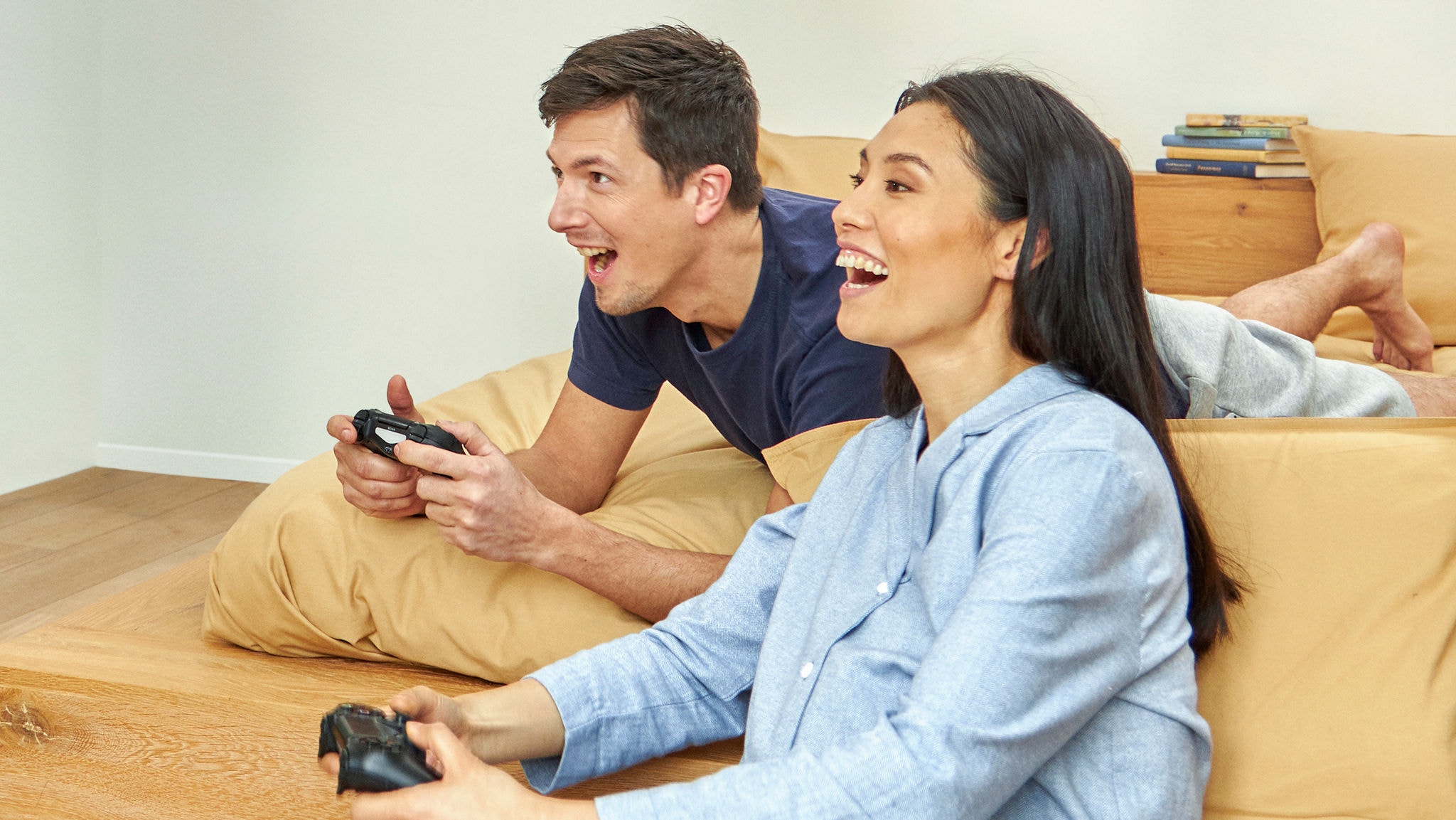 Lachendes Pärchen beim Spielen von Videospielen in einem gemütlichen Raum mit angenehmer Temperatur