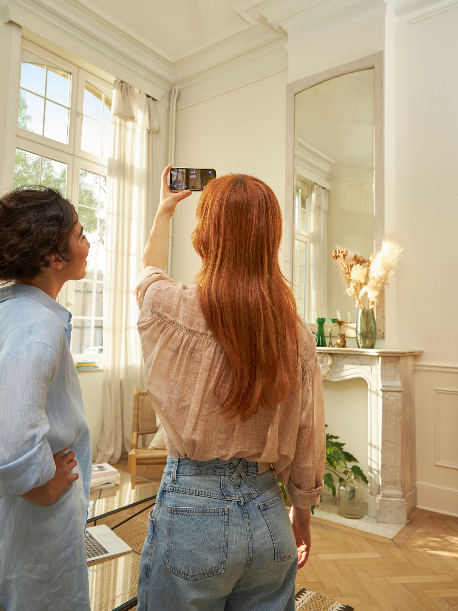 Eine Frau sieht sich in der 3D-App an, wie das Innengerät einer Luft-Luft-Wärmepumpe in ihrem Wohnzimmer wirkt