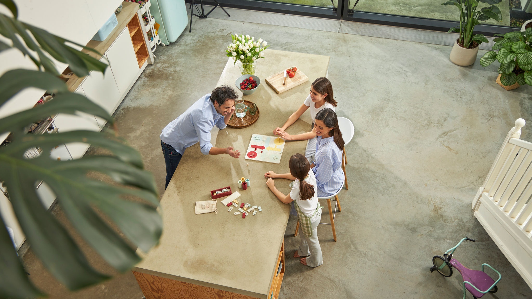 Eine vierköpfige Familie spielt bei optimaler Raumtemperatur am Küchentisch Brettspiele