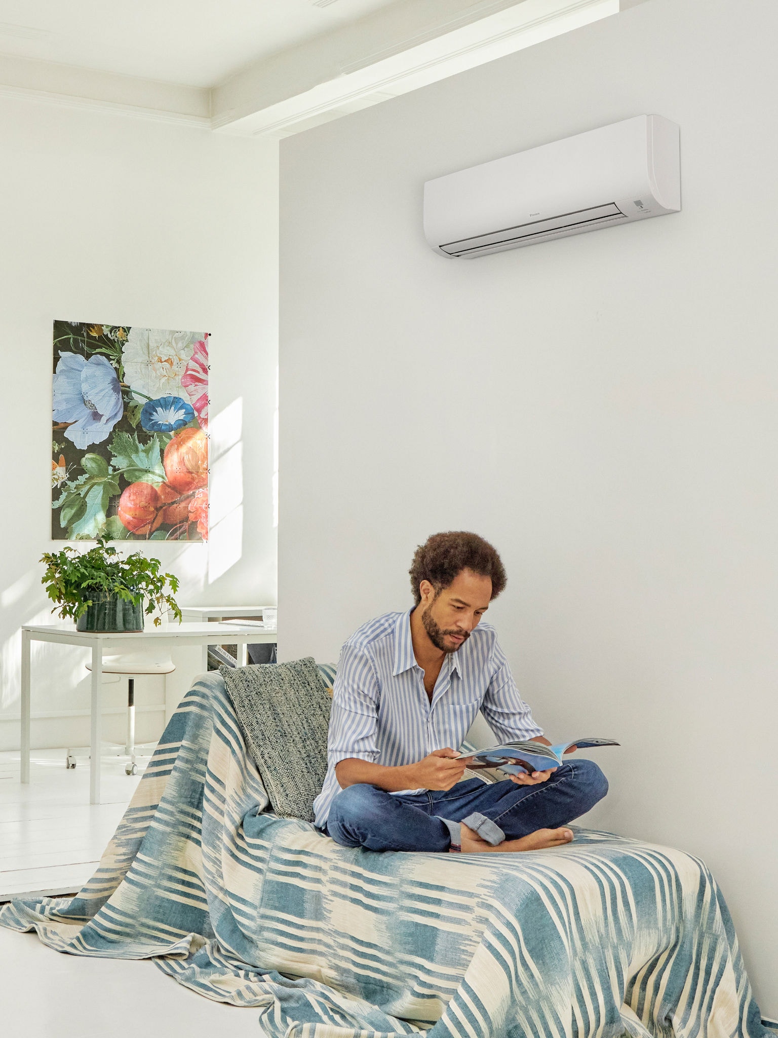 Mann beim Lesen in einem hellen, modernen Wohnraum mit einer an der Wand montierten Wärmepumpe, die den Komfort und die Energieeffizienz der durch staatliche Förderprogramme unterstützten Wärmepumpentechnologie veranschaulicht