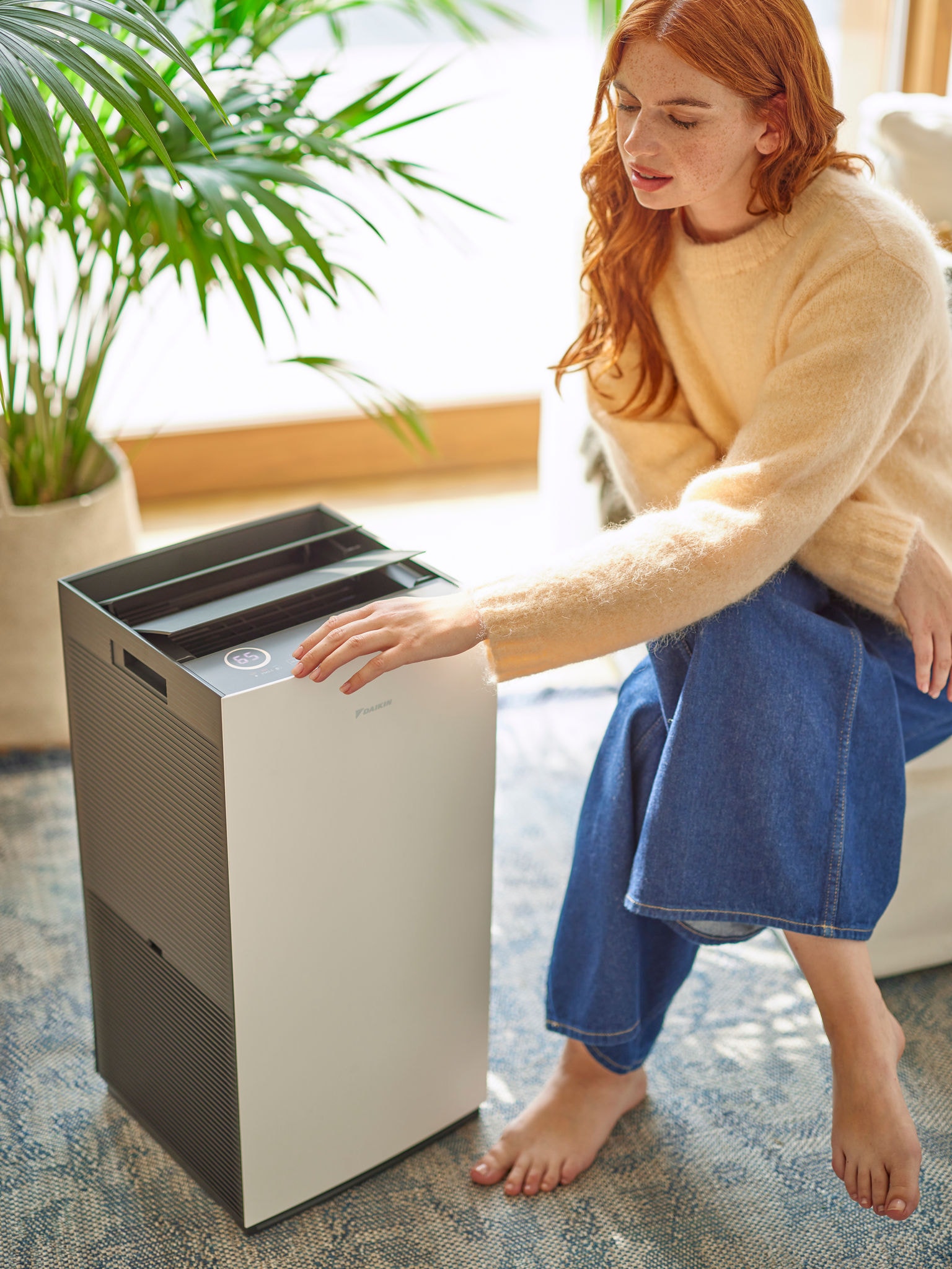 Eine Frau im Wohnbereich stellt die Bedienelemente eines Daikin Luftreinigers ein