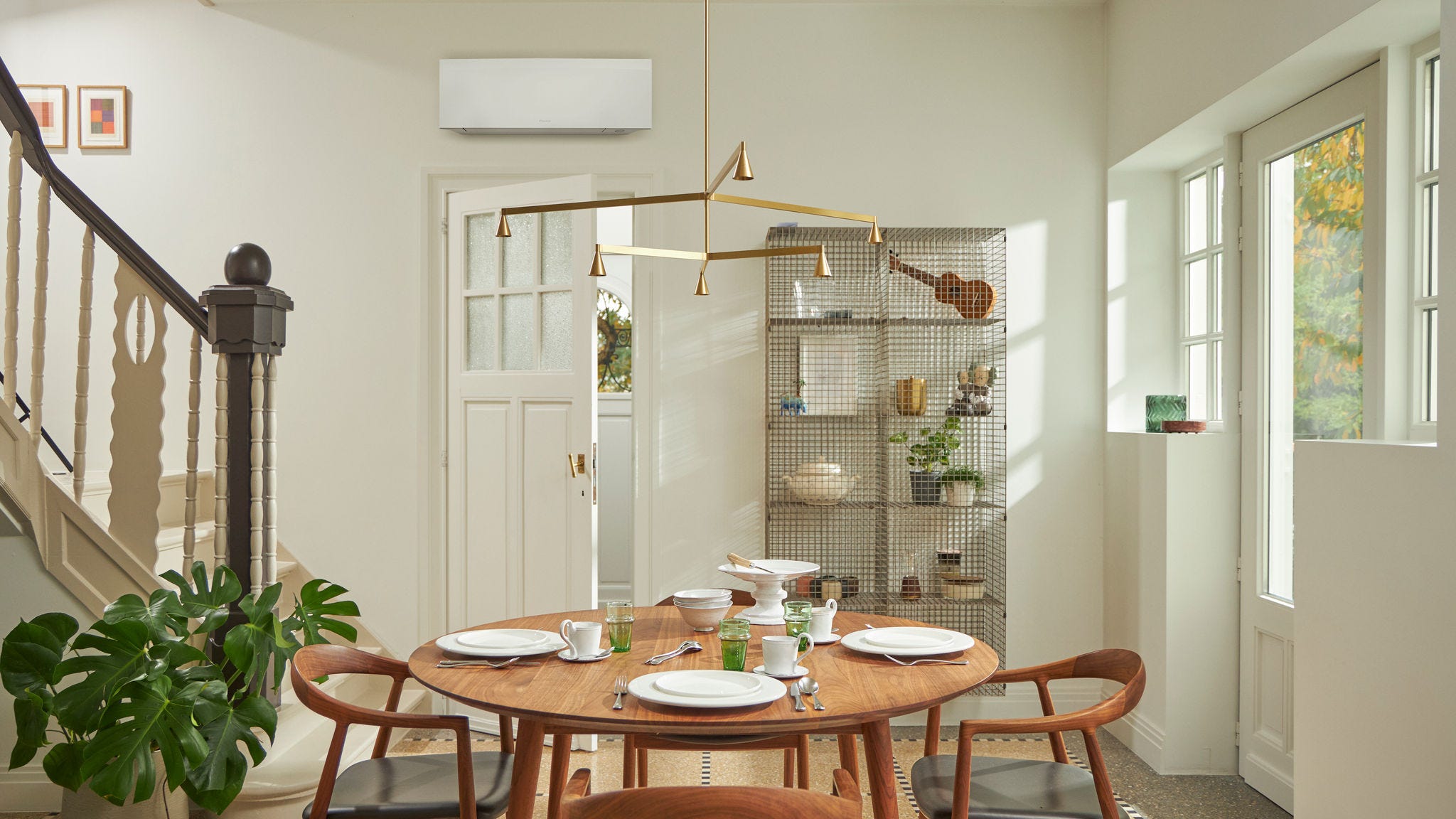 Raum mit großem Fenster, Holztisch und schwarzer, wandmontierter Klimaanlage