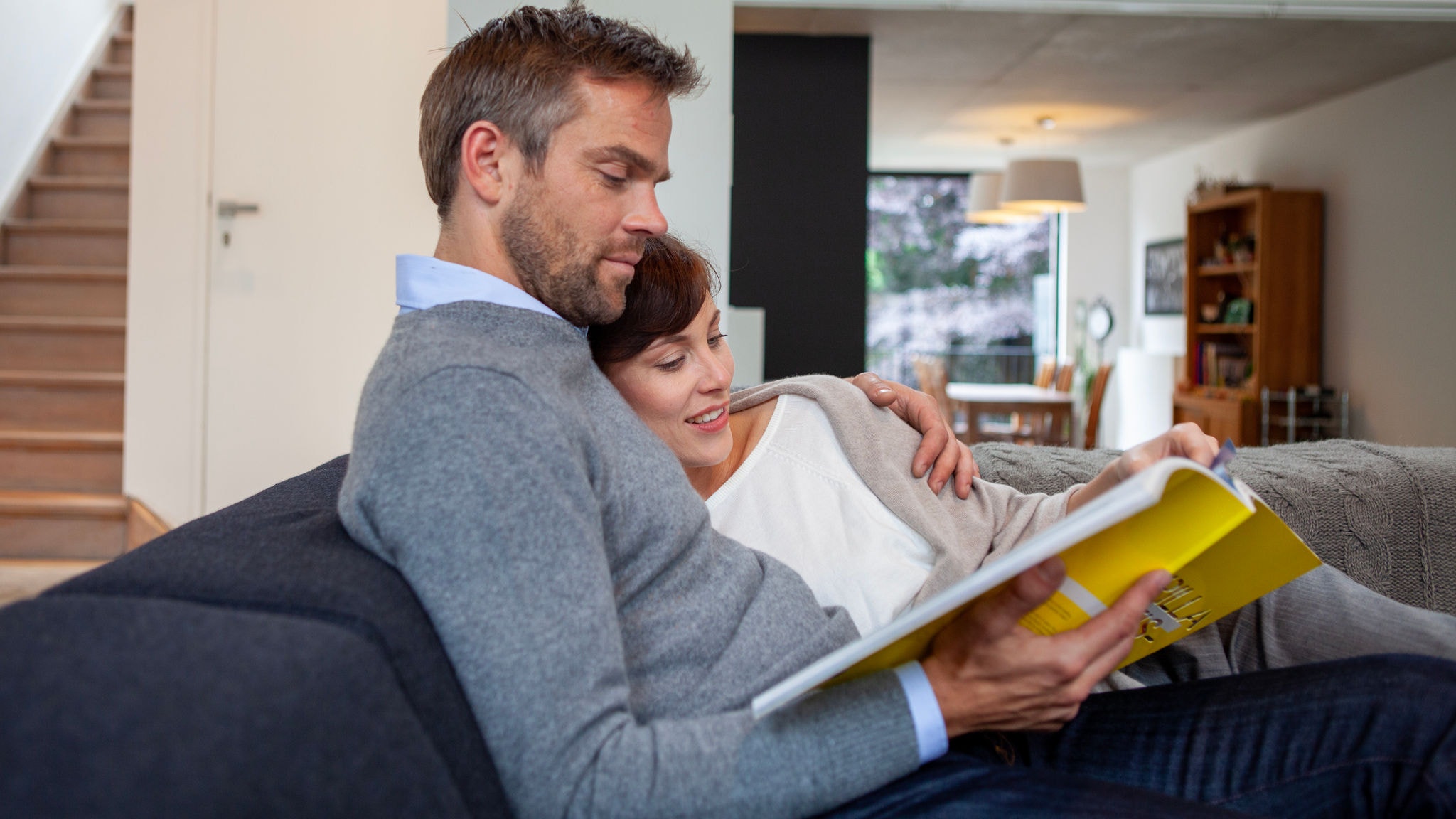 Ein Paar sitzt lesend auf einem Sofa und genießt dank der Klimaanlage „Stylish“ die perfekte Raumtemperatur