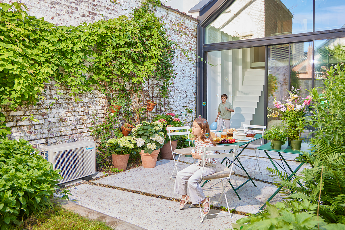 Murmeln spielende Kinder auf einer Gartenterrasse neben einem Wärmepumpen-Außengerät