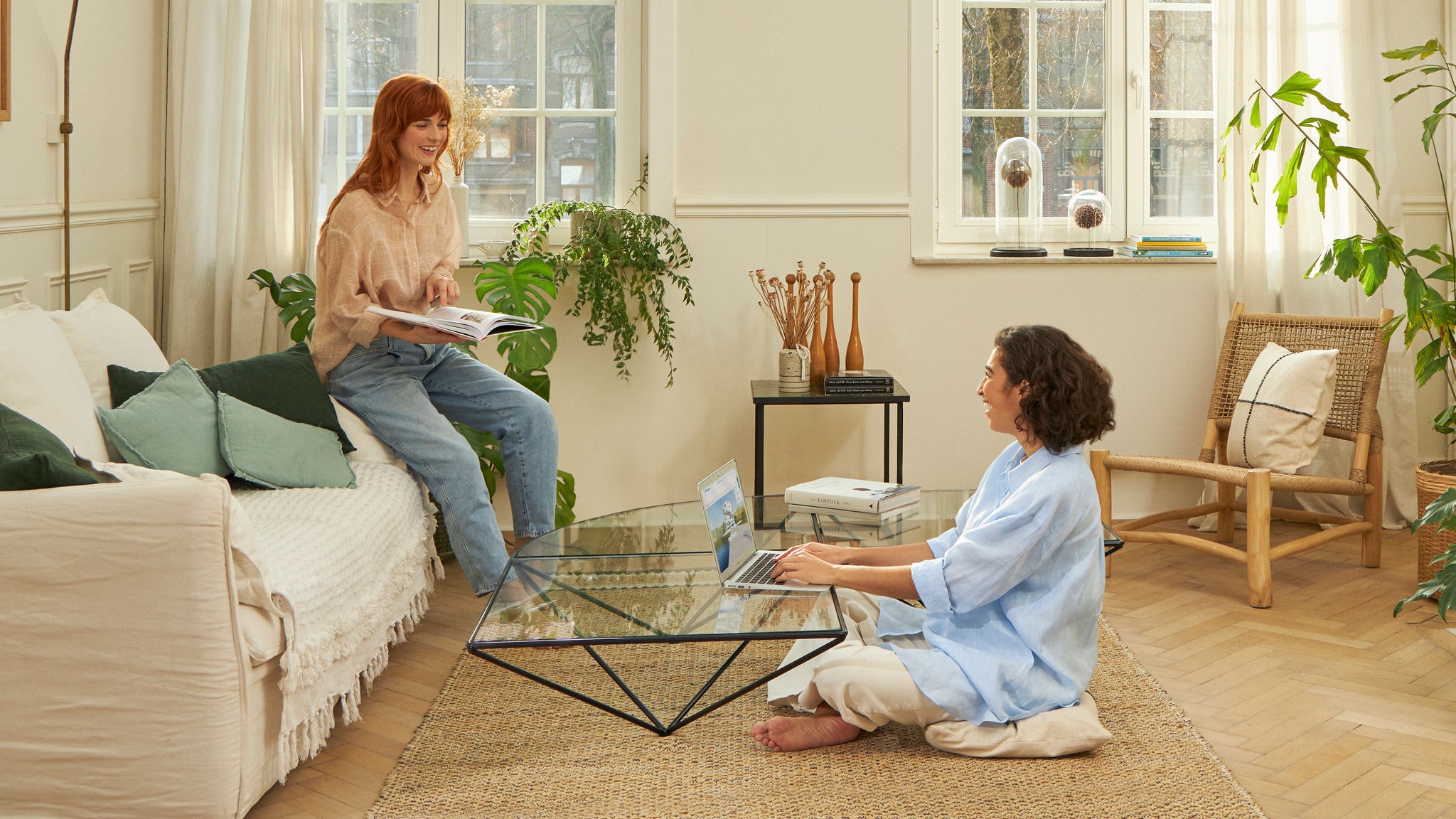 Zwei lachende Frauen im Wohnzimmer arbeiten und lesen